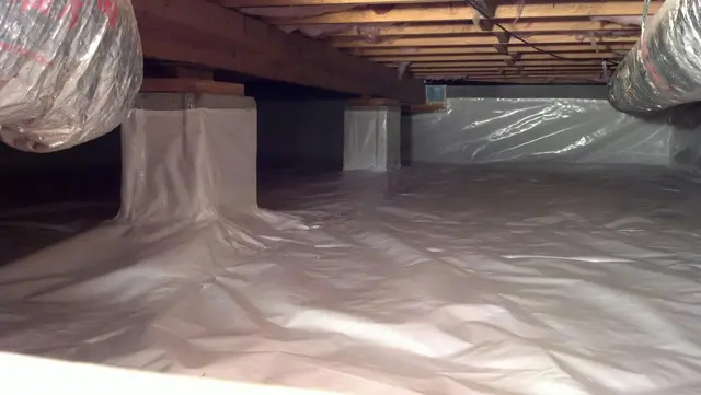 Clean and dry crawl space with a new vapor barrier installation, protecting against moisture.