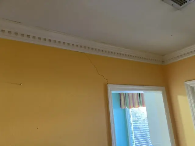 A diagonal crack in an interior wall near the ceiling.