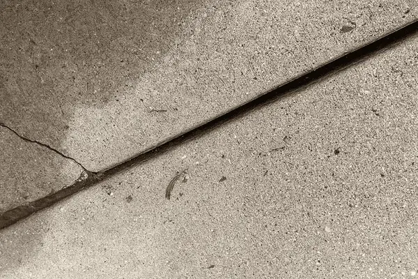 Ground Up Foundation Repair, Waterproofing and Concrete Leveling inspecting a diagonal concrete crack near a control joint.