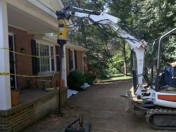 Ground Up Foundation Repair, Waterproofing and Concrete Leveling installing a foundation pier with an excavator for a residen