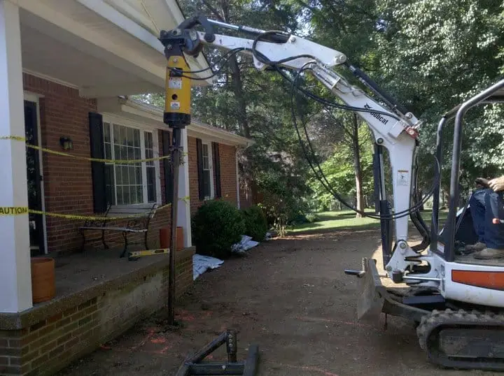 Ground Up Foundation Repair, Waterproofing and Concrete Leveling installing a foundation pier with an excavator for a residen