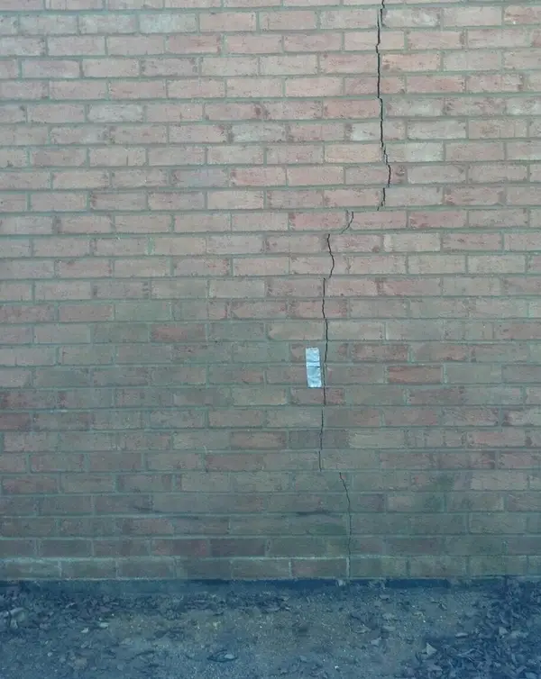 A vertical crack running through an exterior brick wall.