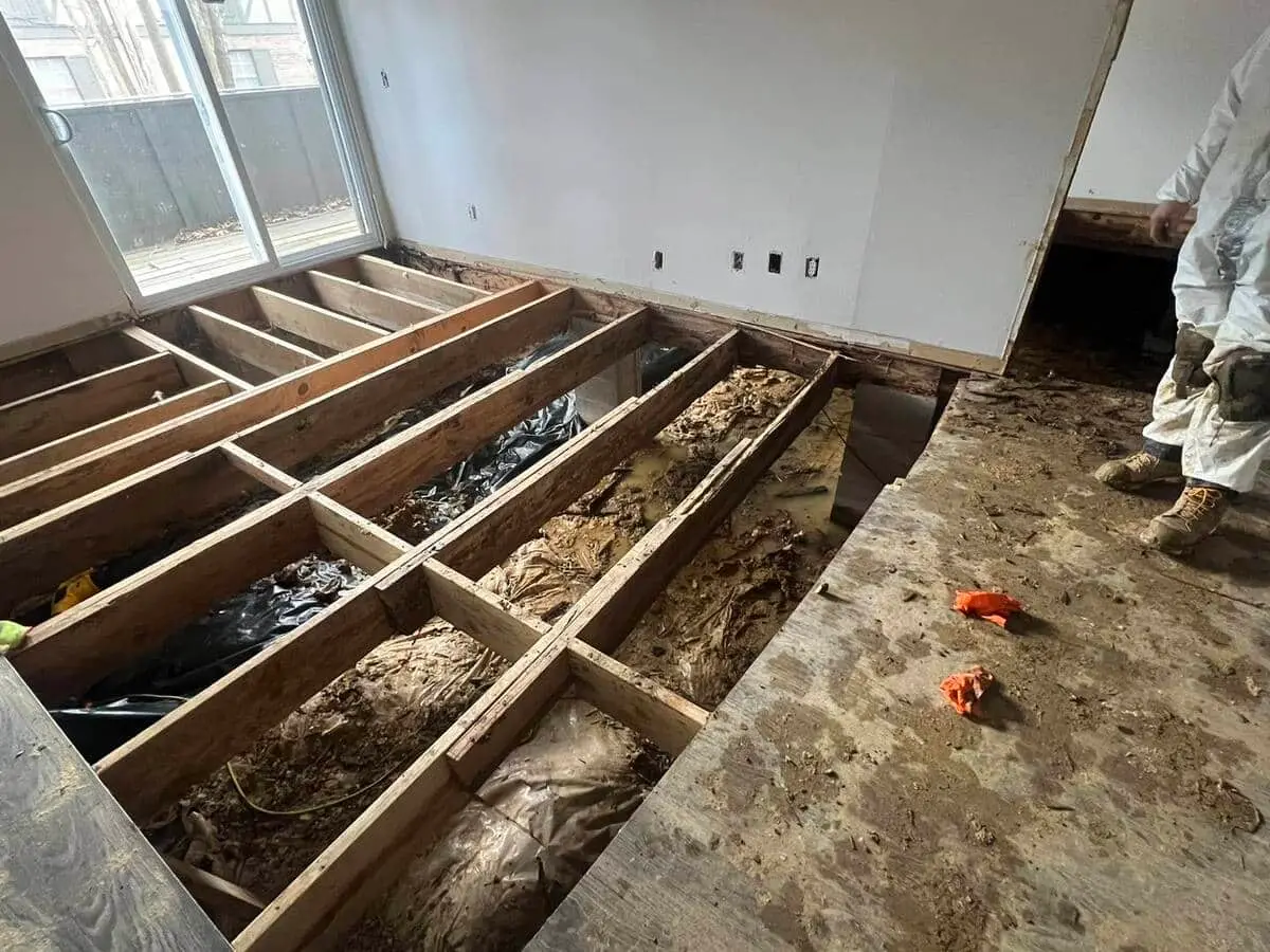 Severe basement flooding with exposed floor joists and structural damage from water.