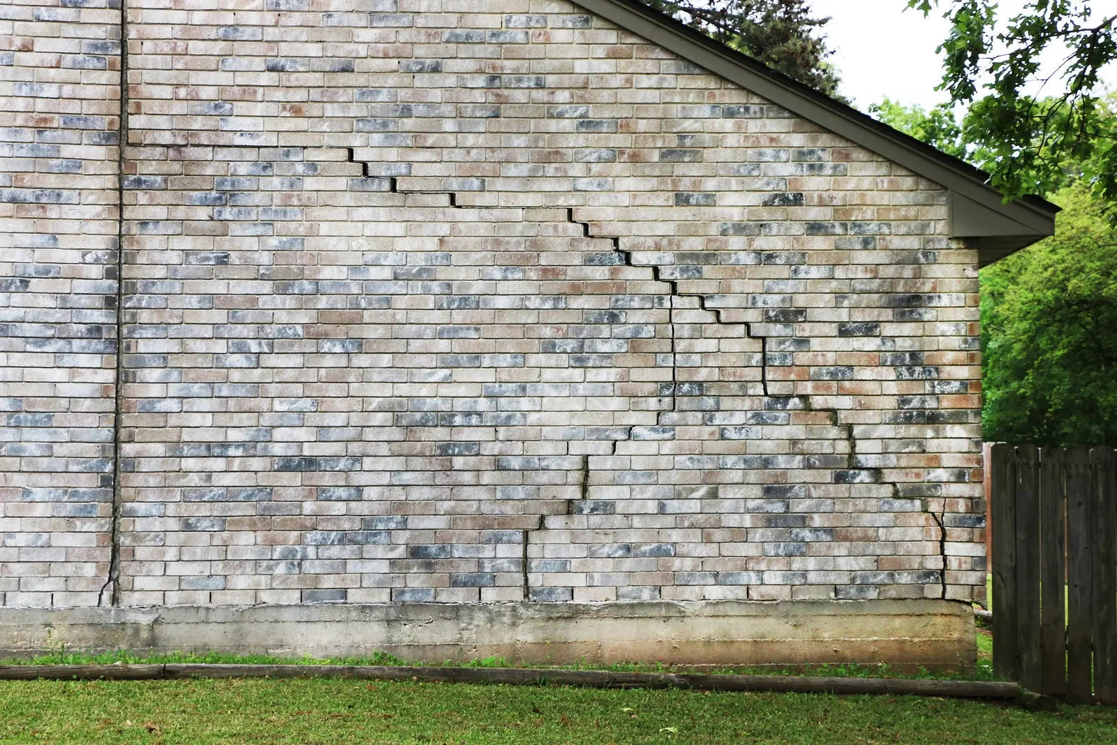 Ground Up Foundation Repair, Waterproofing and Concrete Leveling inspecting stair-step foundation crack on a brick exterior w