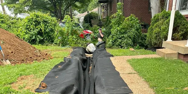 Installing a French drain with pipe and filter fabric for yard drainage.
