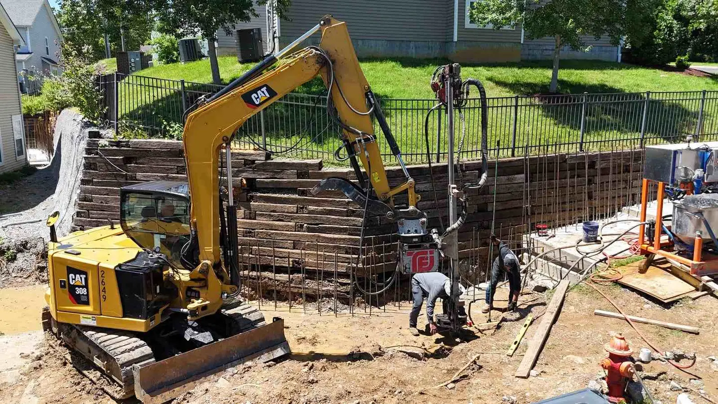 Ground Up Foundation Repair, Waterproofing and Concrete Leveling crew performing commercial foundation repair with an excavat