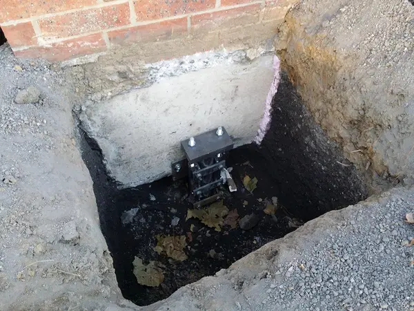 Ground Up Foundation Repair, Waterproofing and Concrete Leveling installing a new foundation pier for structural stabilizatio