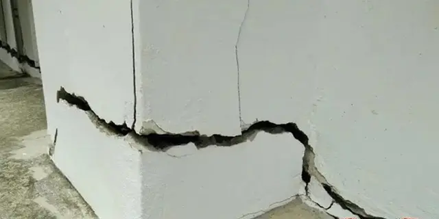 Inspecting a severe foundation crack and the surrounding structural damage.