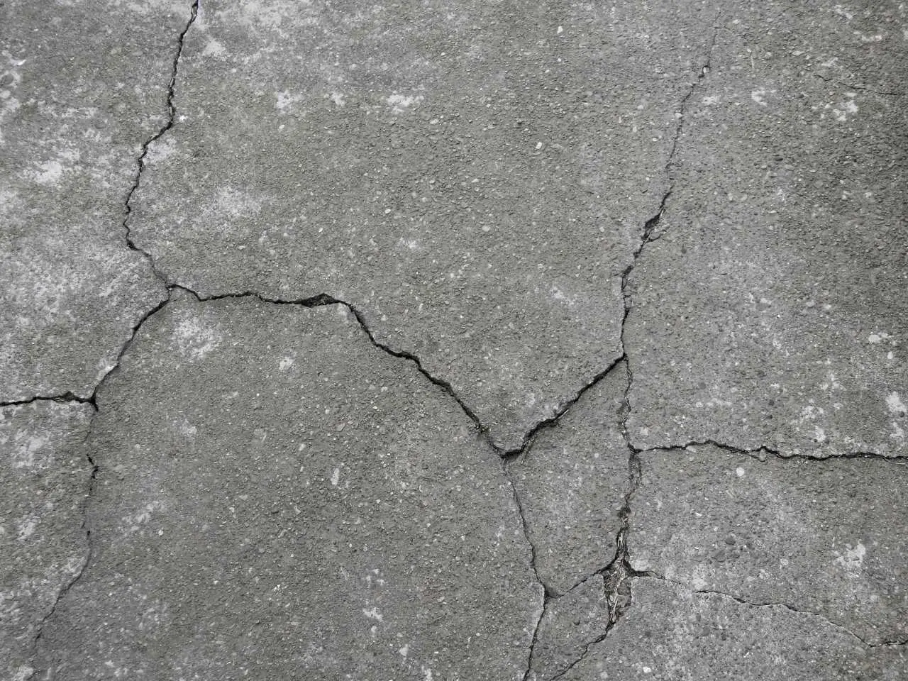 Cracks in a concrete driveway or patio surface.