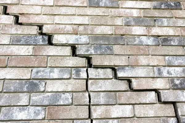 Stair step cracks in a home exterior brick wall.
