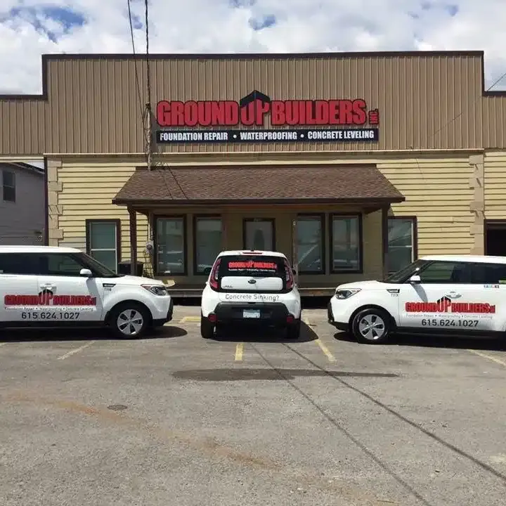 Branded Ground Up Foundation Repair trucks and trailers parked outside the company office.