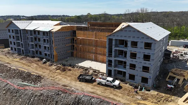 A multi-family apartment building under construction with a Ground Up service truck on site.
