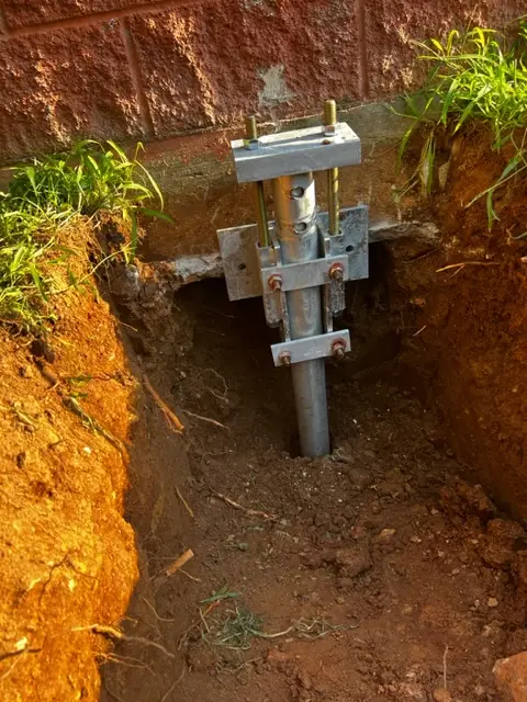 Ground Up Foundation Repair, Waterproofing and Concrete Leveling installing a helical pier system for foundation