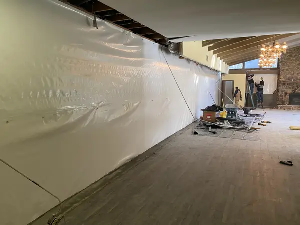 A Ground Up Foundation Repair crew installing a wall vapor barrier along a basement interior.