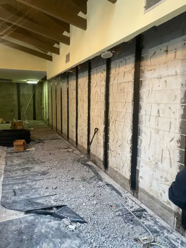 Ground Up Foundation Repair, Waterproofing and Concrete Leveling installing carbon fiber straps for basement wall