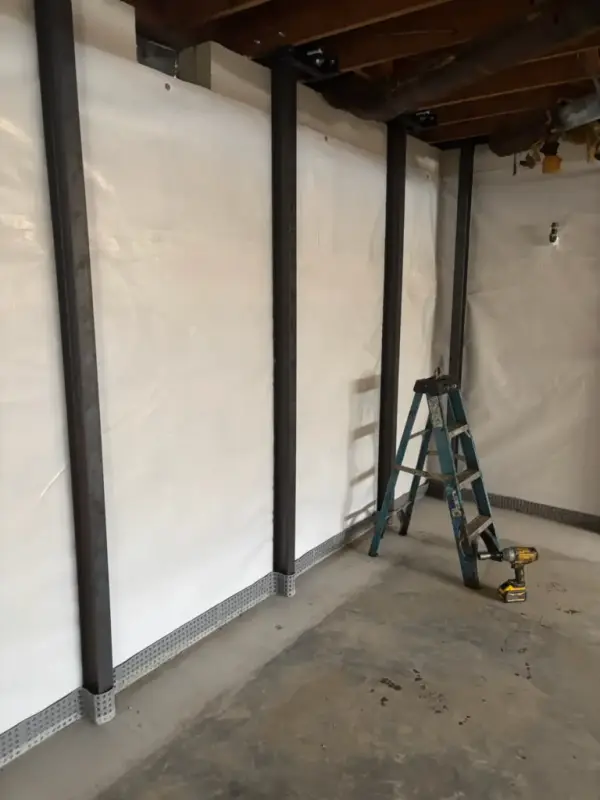 Ground Up Foundation Repair, Waterproofing and Concrete Leveling installing I-beam wall bracing in a basement.