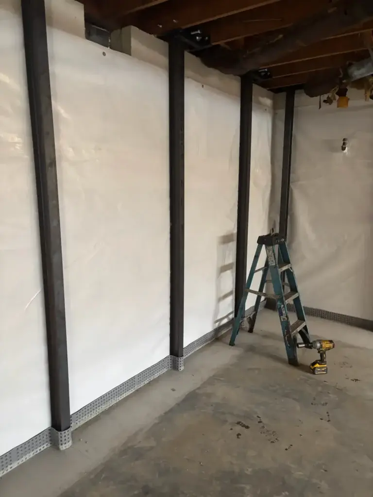 Ground Up Foundation Repair, Waterproofing and Concrete Leveling installing I-beam wall bracing in a basement.